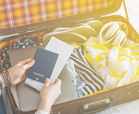 person packing their suitcase for a trip holding important documents