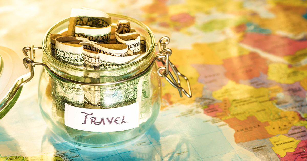 A jar with dollar bills in it on a map that reads "travel"