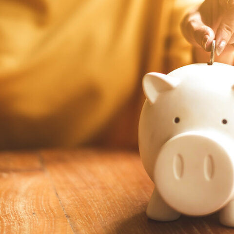 Hand placing money into a piggy bank