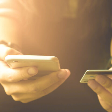 Man holding phone in one hand and credit card in the other hand