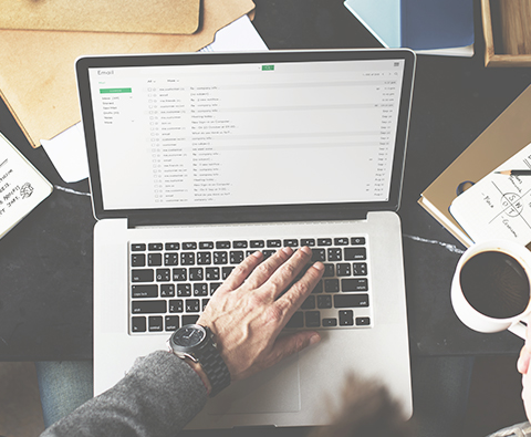 small business owner working on laptop with a cup of coffee in hand