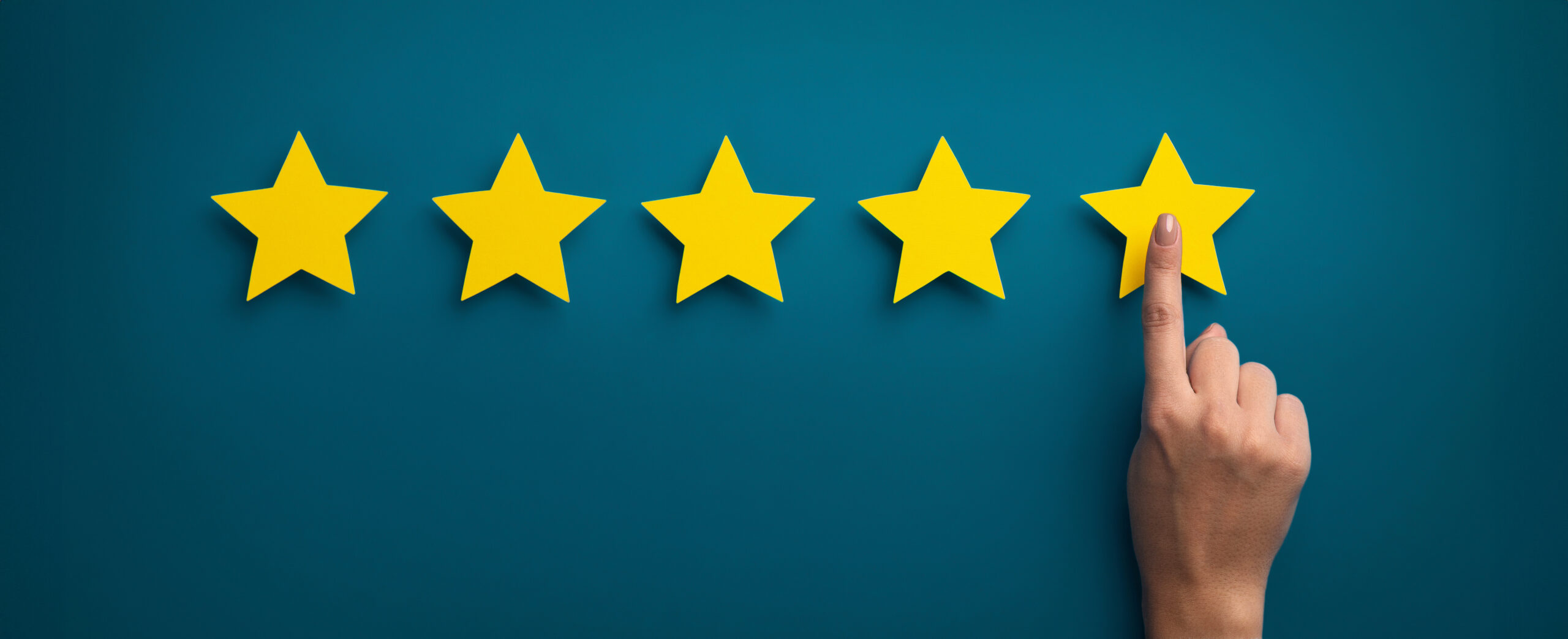 Hand arranging five gold stars on a dark background.