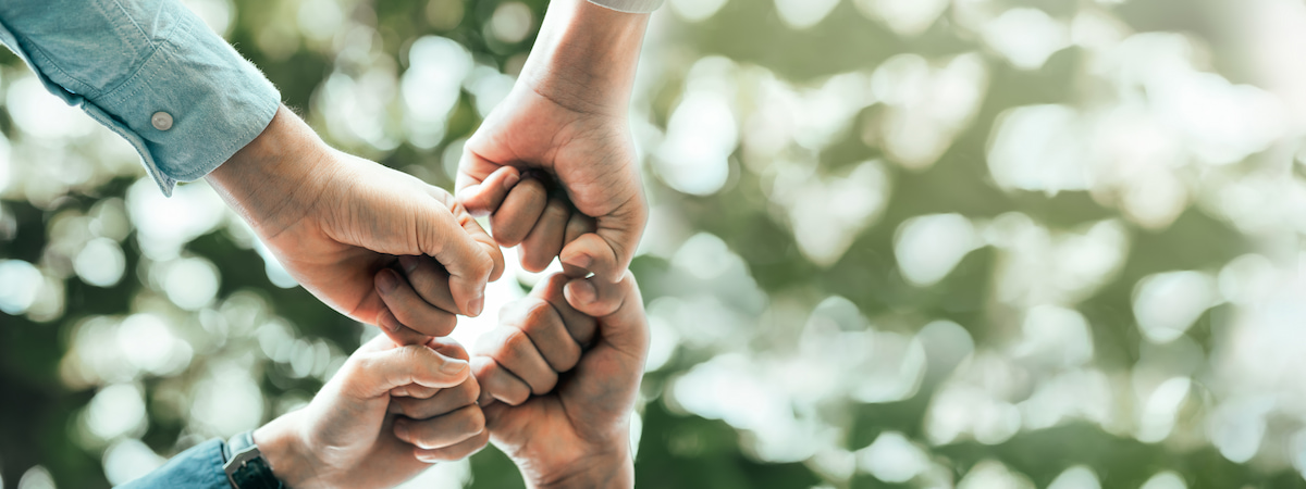 Four people fist-bumping each other in solidarity.